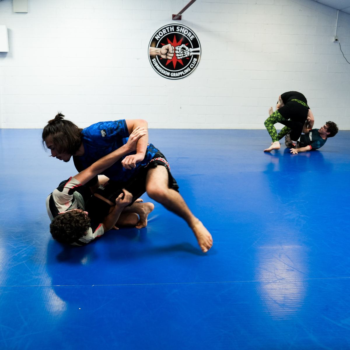 Two grapplers working ground position during no-gi training at North Shore Submission Grappling, Takapuna